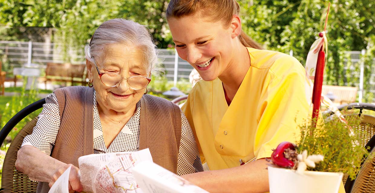 Pflegefachkraft draußen mit Bewohnerin